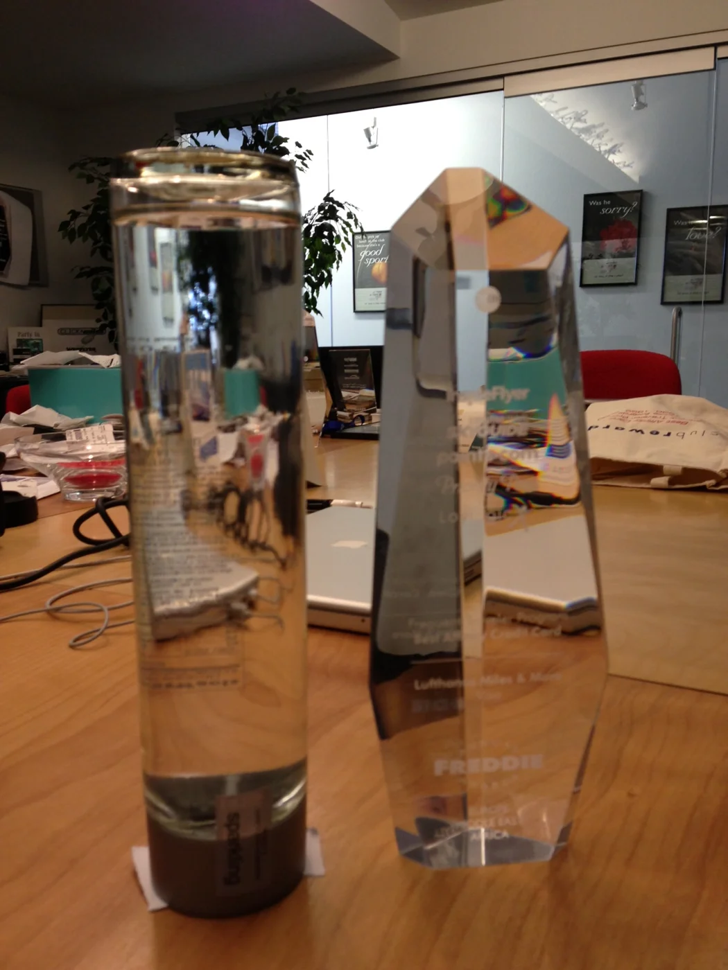 The original faceted crystal obelisk Freddie Award beside a bottle for scale